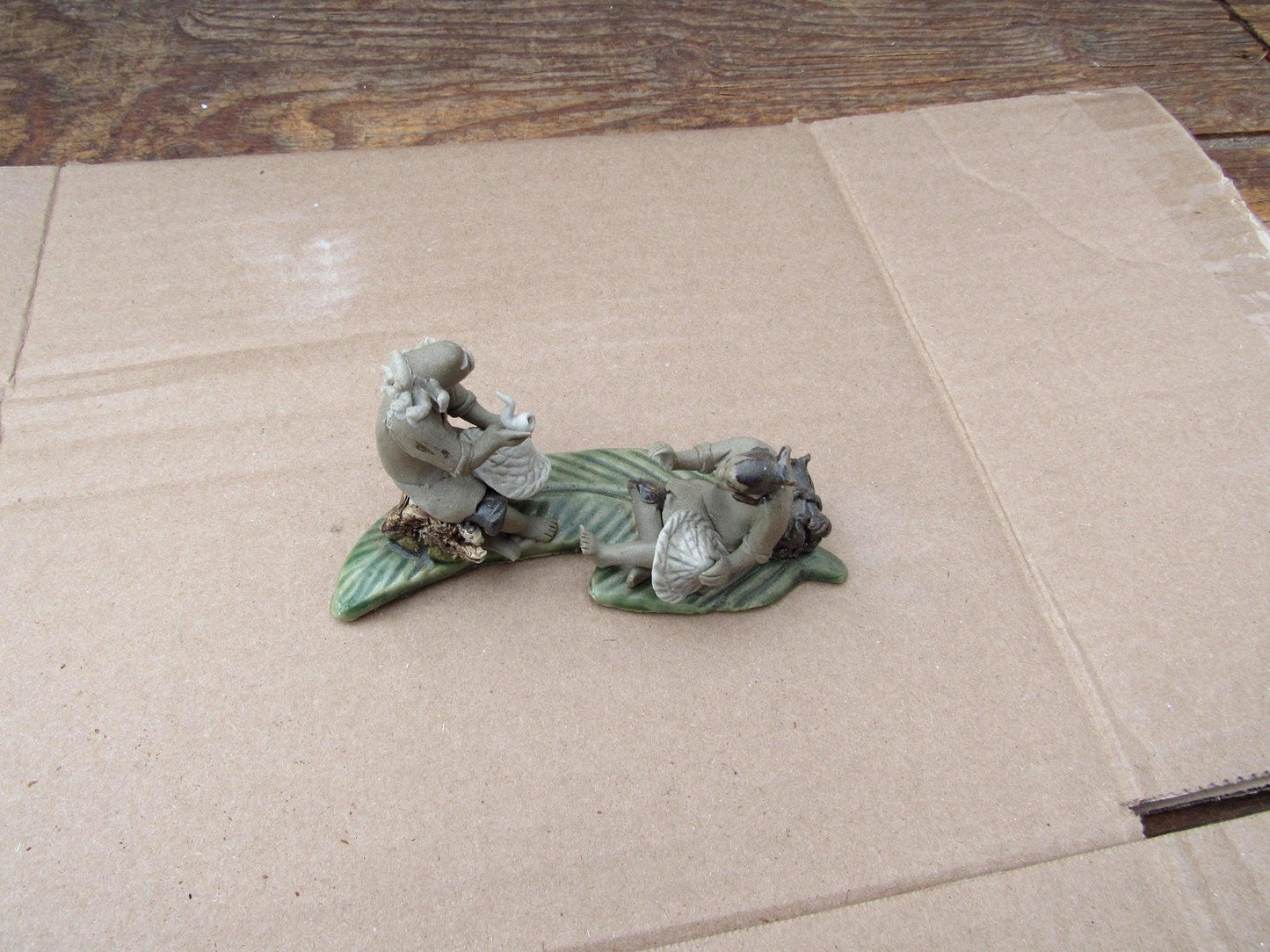 Two Mud Men Smoking On A Leaf Figurine