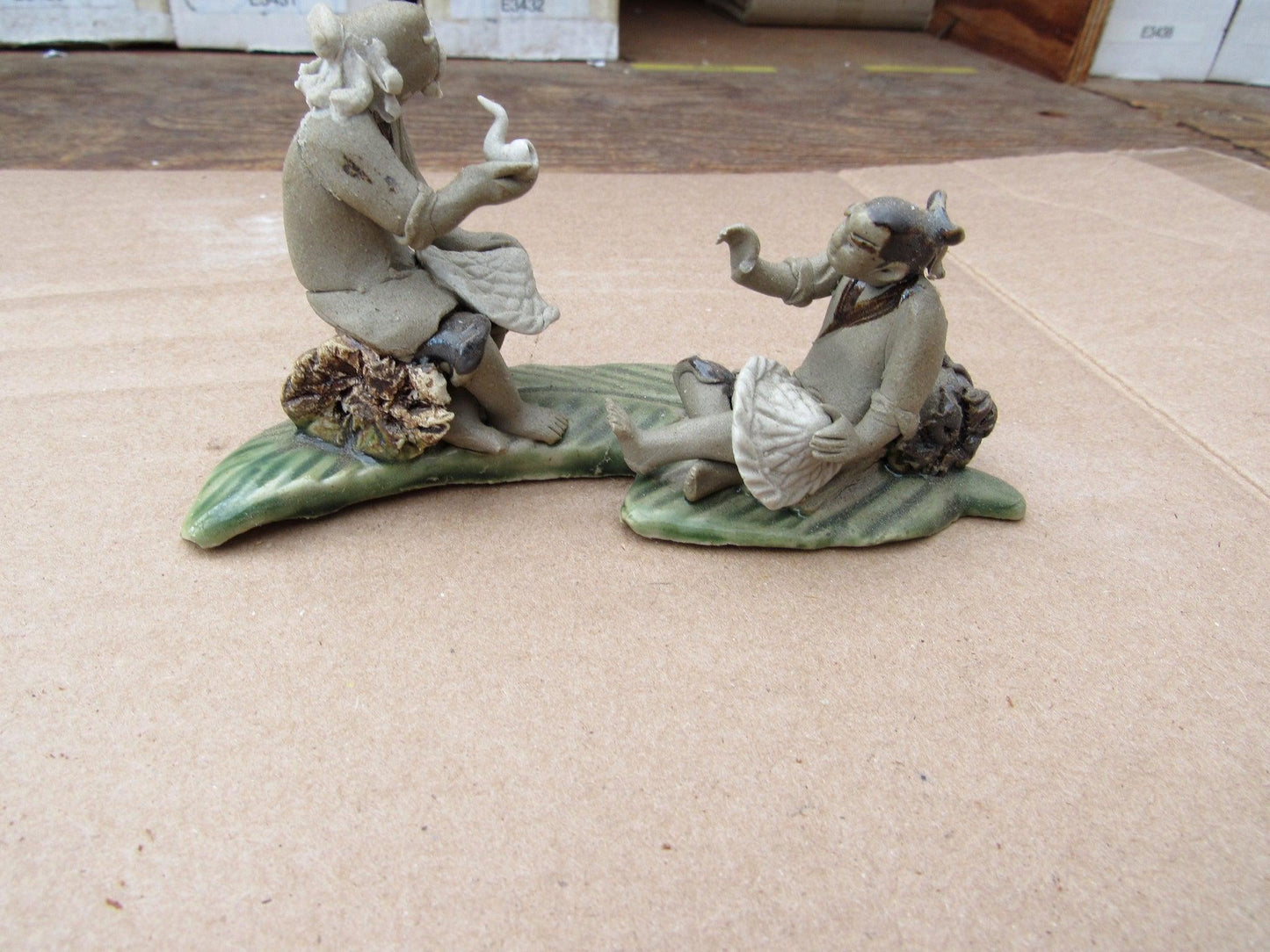 Two Mud Men Smoking On A Leaf Figurine